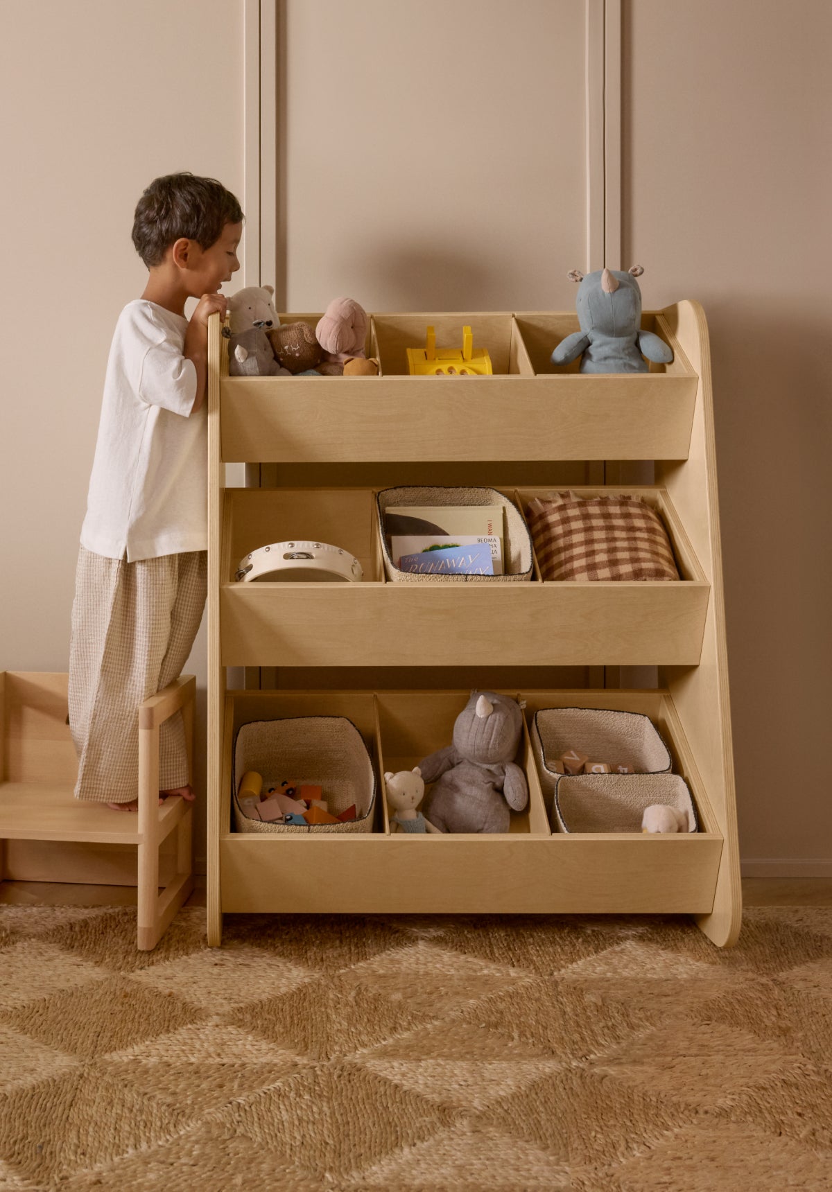 A child accessing toys in a Piccalio toy organizer made of natural wood with a non-toxic finish