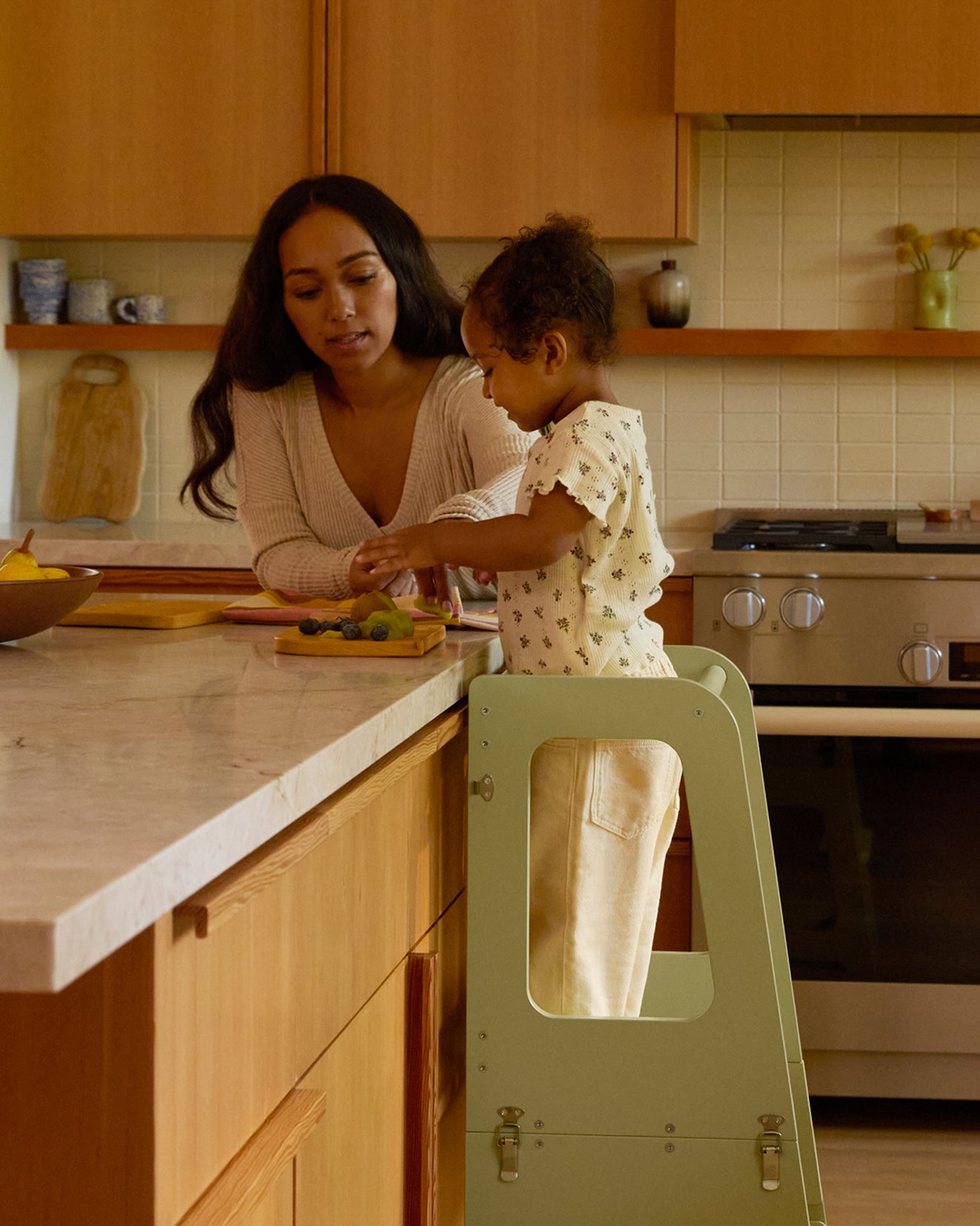 Mother and child in the kitchen using a convertible helper tower, child on a toddler tower in sage