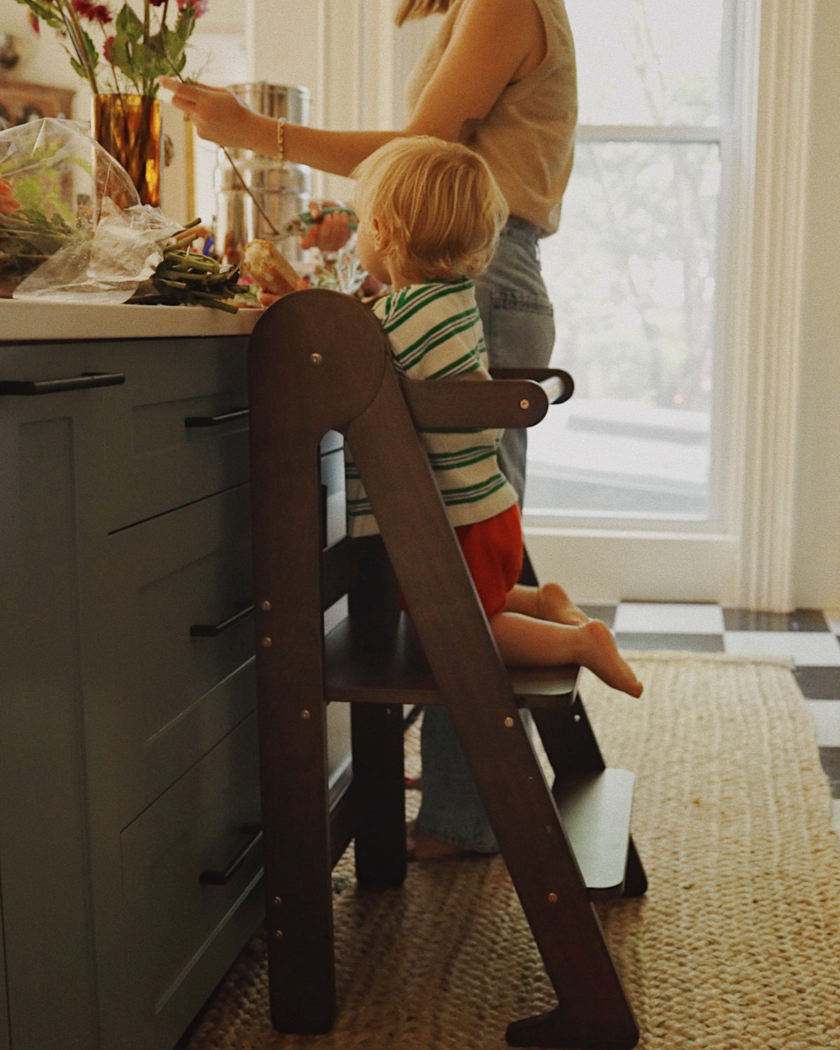 Child climbing up on a walnut colored Piccalio Foldable Toddler Tower made of natural wood