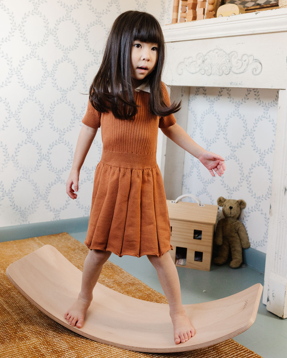 girl balancing playing with wooden toys