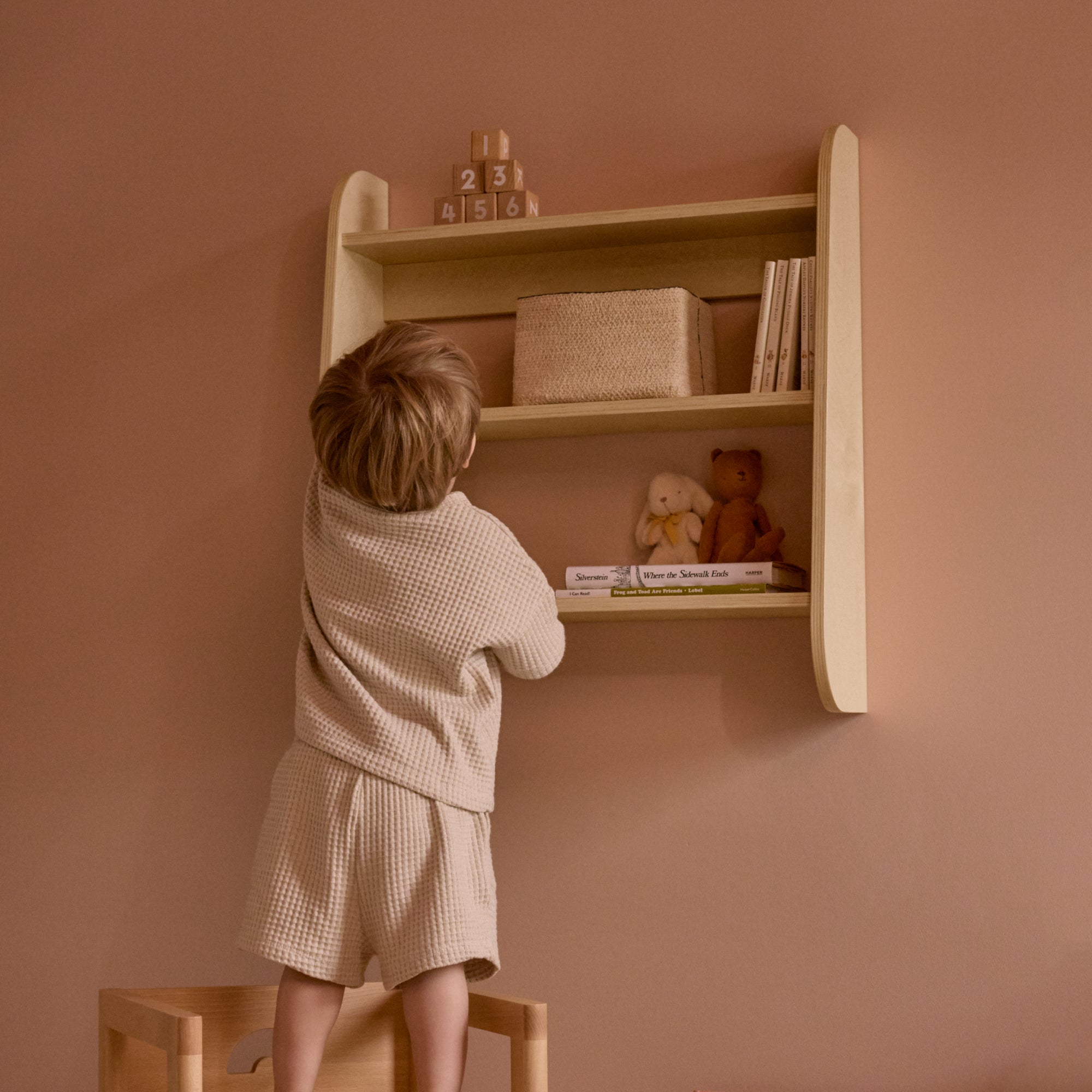 child reaching for toys from Piccalio wall shelf, wall mounted bookshelves, bedroom shelves, nursery wall shelves