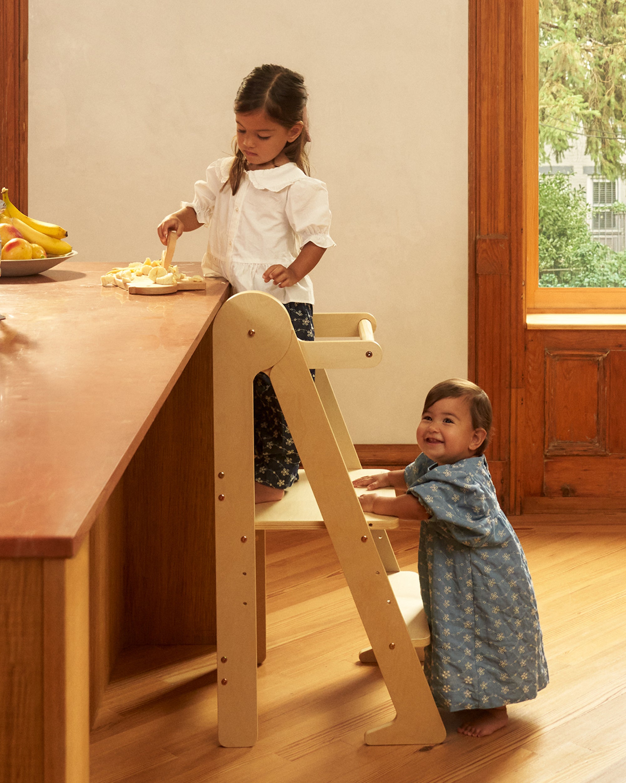 Piccalio foldable toddler tower in birch wood used by a child in the kitchen.
