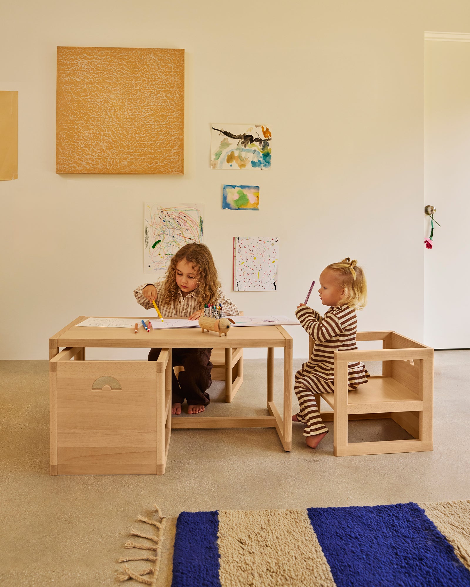 Two toddlers using a Piccalio large Montessori play table and matching wooden chairs in natural beech.
