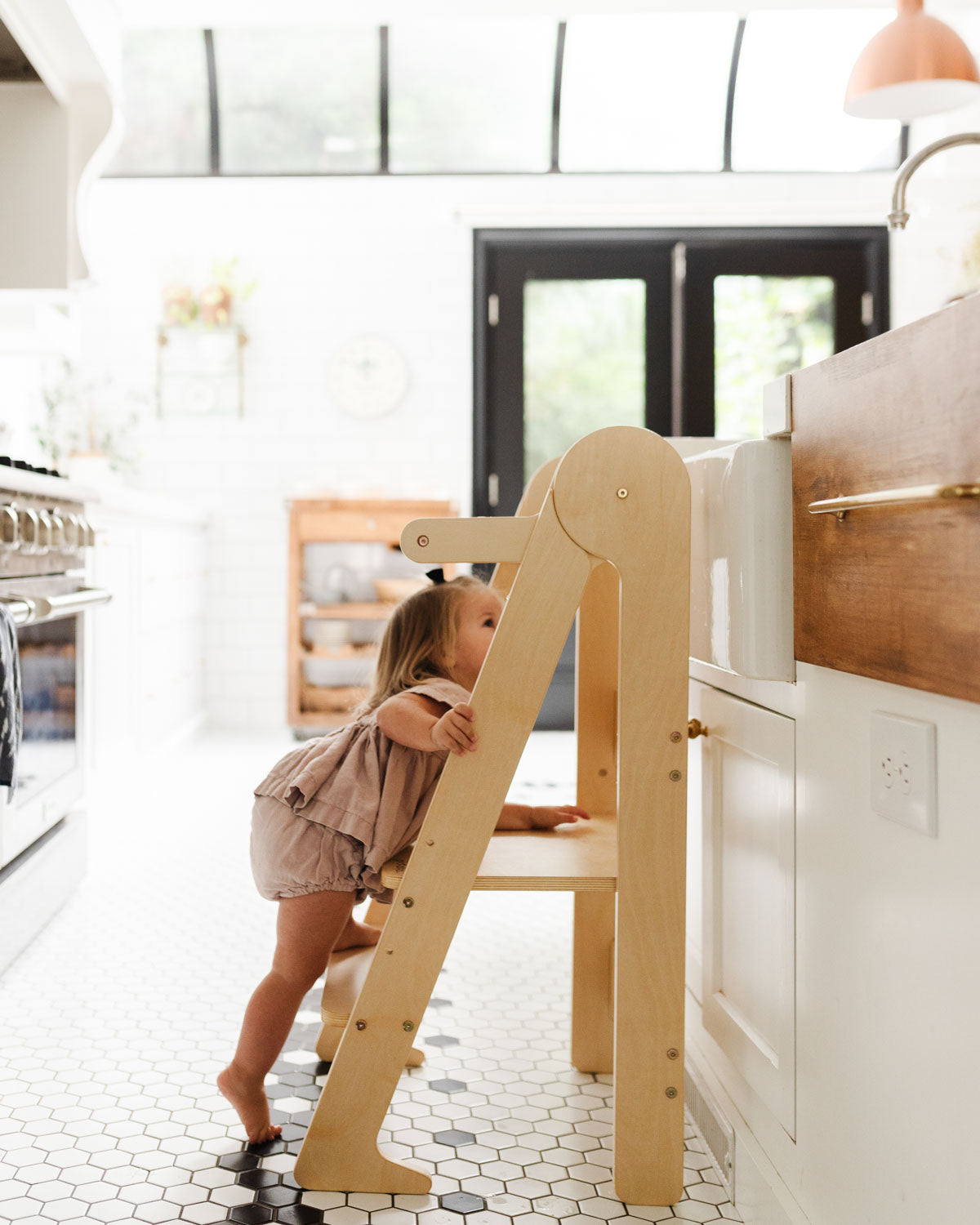 Piccalio foldable learning tower in birch wood used by a child in the kitchen.
