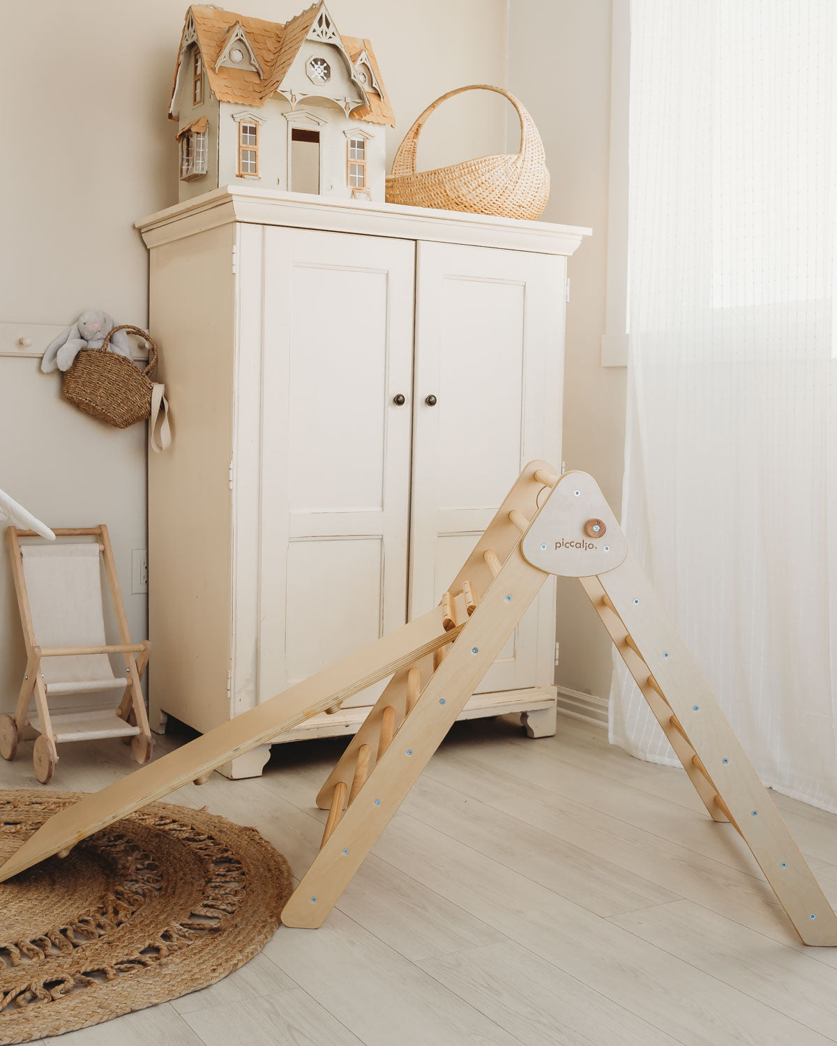 Piccalio Pikler triangle with a reversible slide and climbing ramp in natural wood in a playroom.