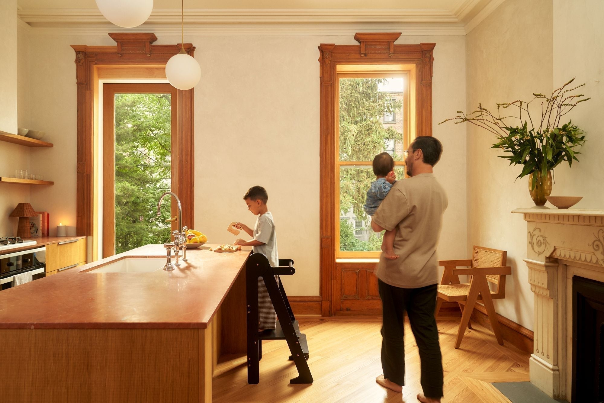 Child uses helper tower in a kitchen as his father walks by. Are toddler towers safe for kids?