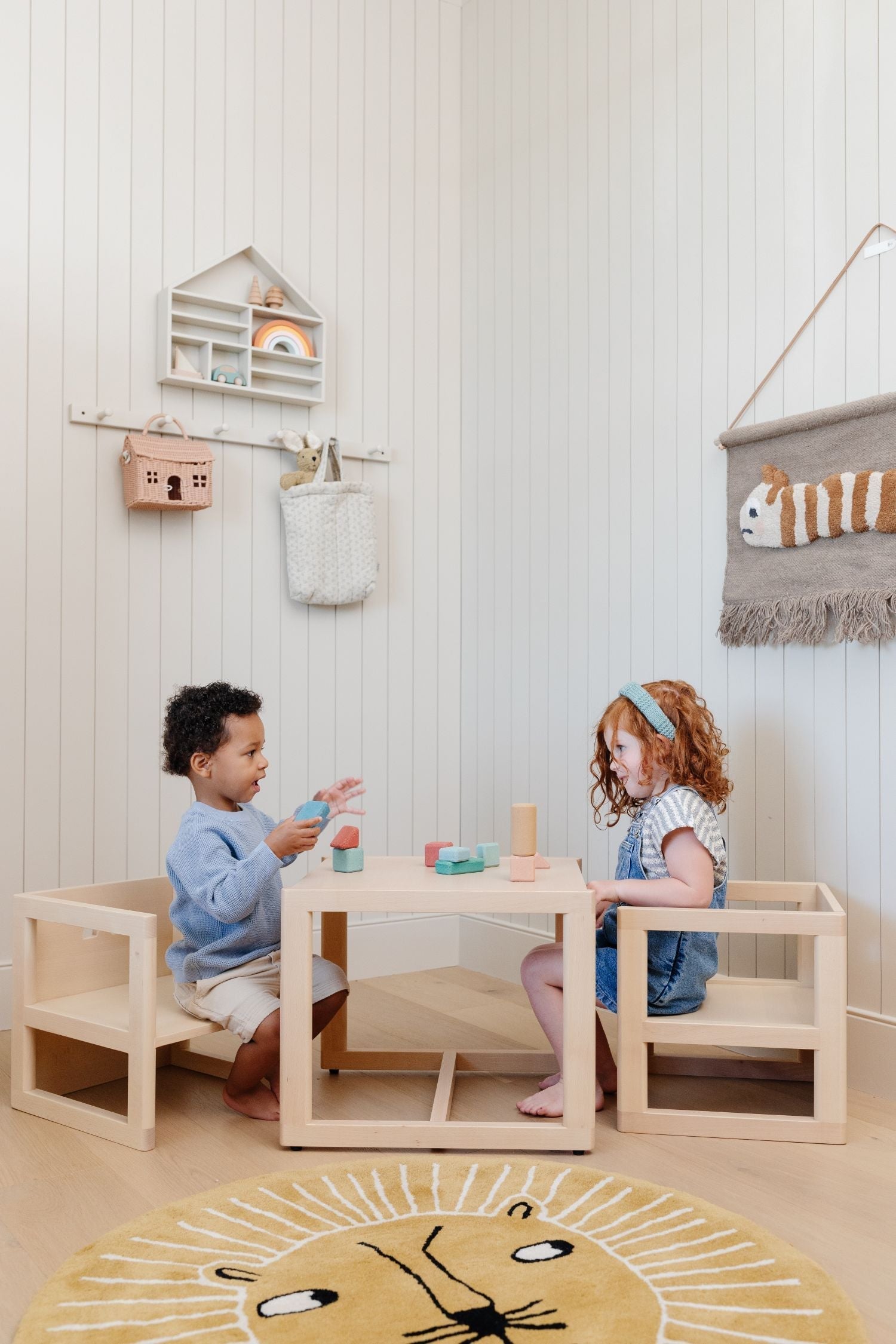 Two children sitting and playing with blocks at a play table made of solid wood