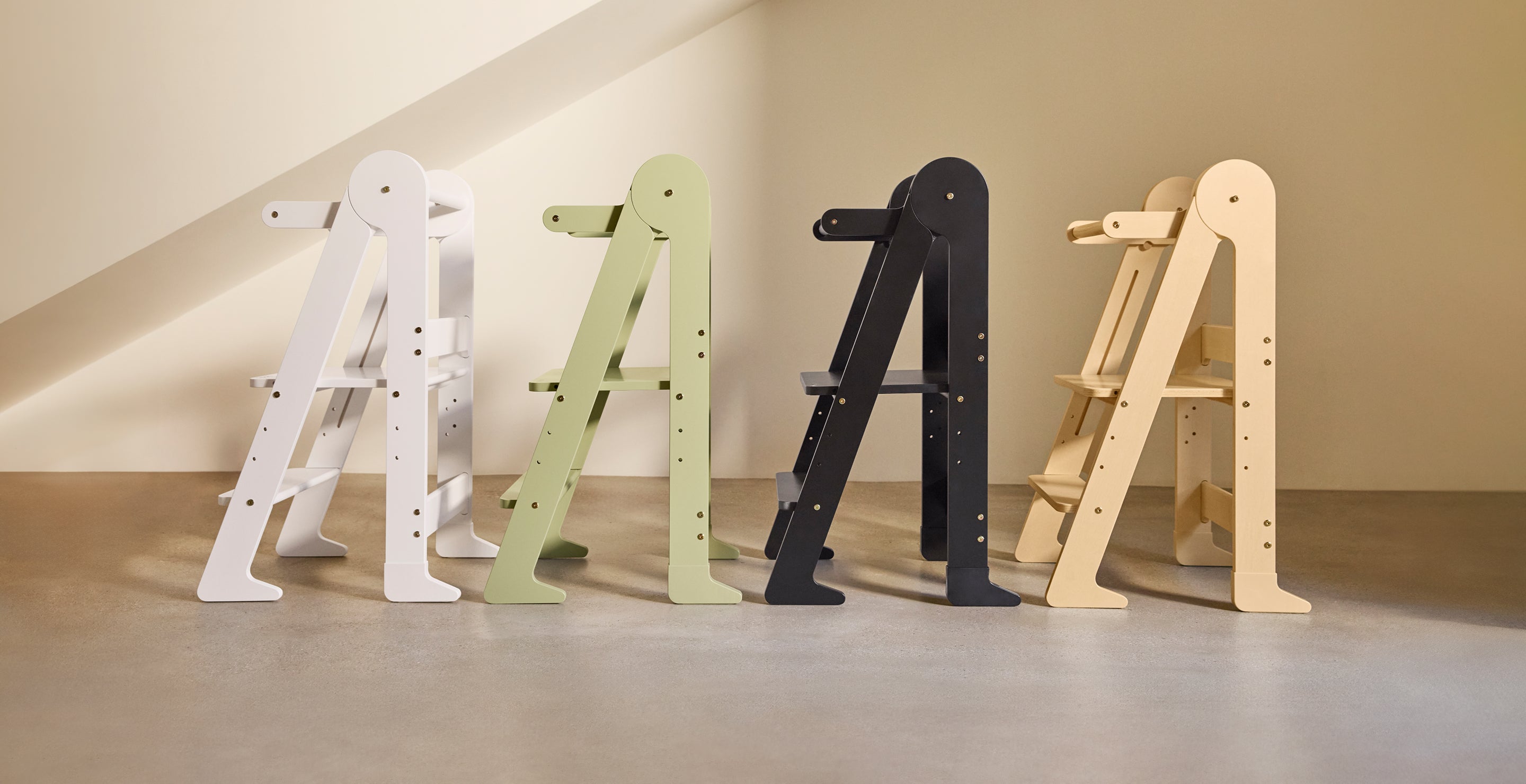 Toddler standing on a foldable toddler tower in birch at a kitchen counter to safely help with cooking and food prep