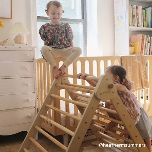 Children playing on the Piccalio Pikler Triangle Set made of natural wood in a child's bedroom