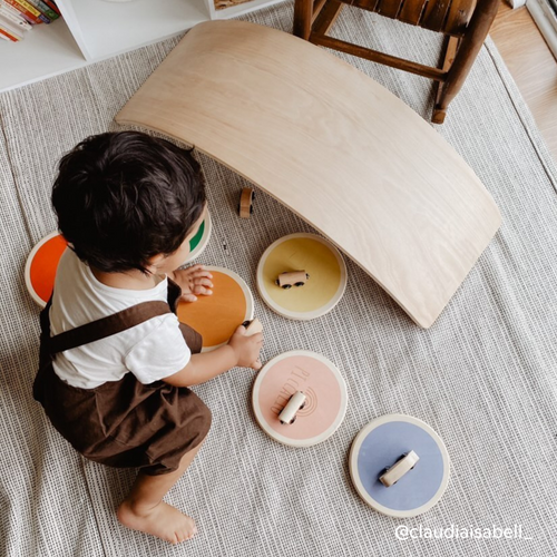 Boy playing with wooden balance board for kids, stepping stones, and toy cars