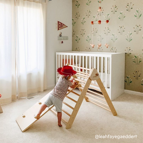 Child climbing the Piccalio Pikler climbing set with rockwall and slide in a nursery