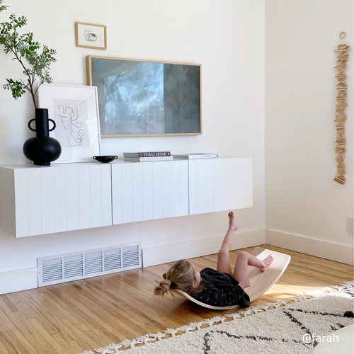 Girl lying on balance board for kids made of birch wood for active play time and screen-free play