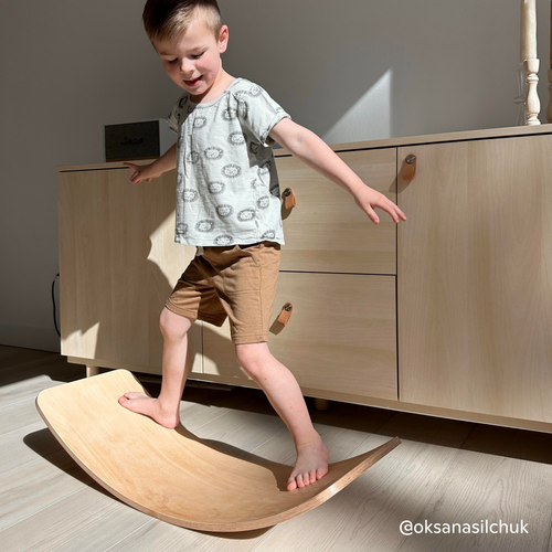 Boy playing on Montessori wooden toy in balance board style in a modern living room 