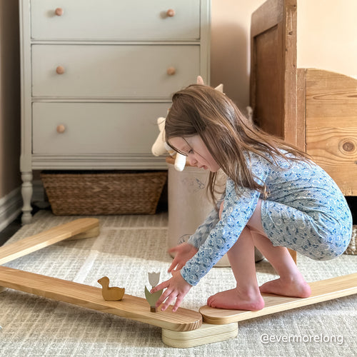 Girl playing with wooden toys on Piccalio wooden balance beam for children in her bedroom