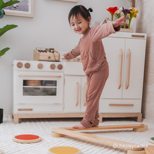 Toddler playing on Piccalio wooden balance beam and stepping stones in a Montessori playroom