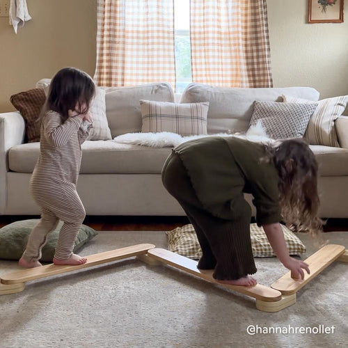 Two children walking on Piccalio balance beam for kids made of natural wood in a modern living room