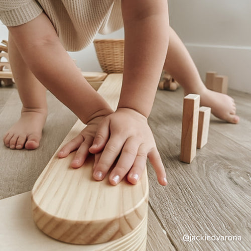 Close-up of child playing with wooden blocks and Montessori balance beam made of natural wood