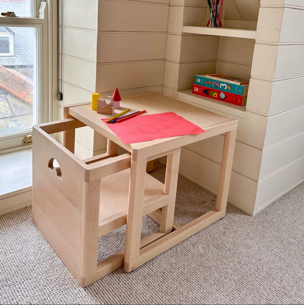 Piccalio Children's wooden desk with chair in a room with a window and shelves.