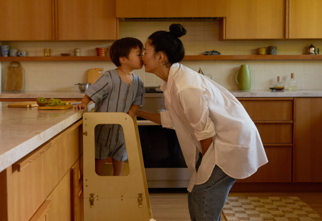 Mom nuzzling son as he stands on Piccalio Convertible helper tower