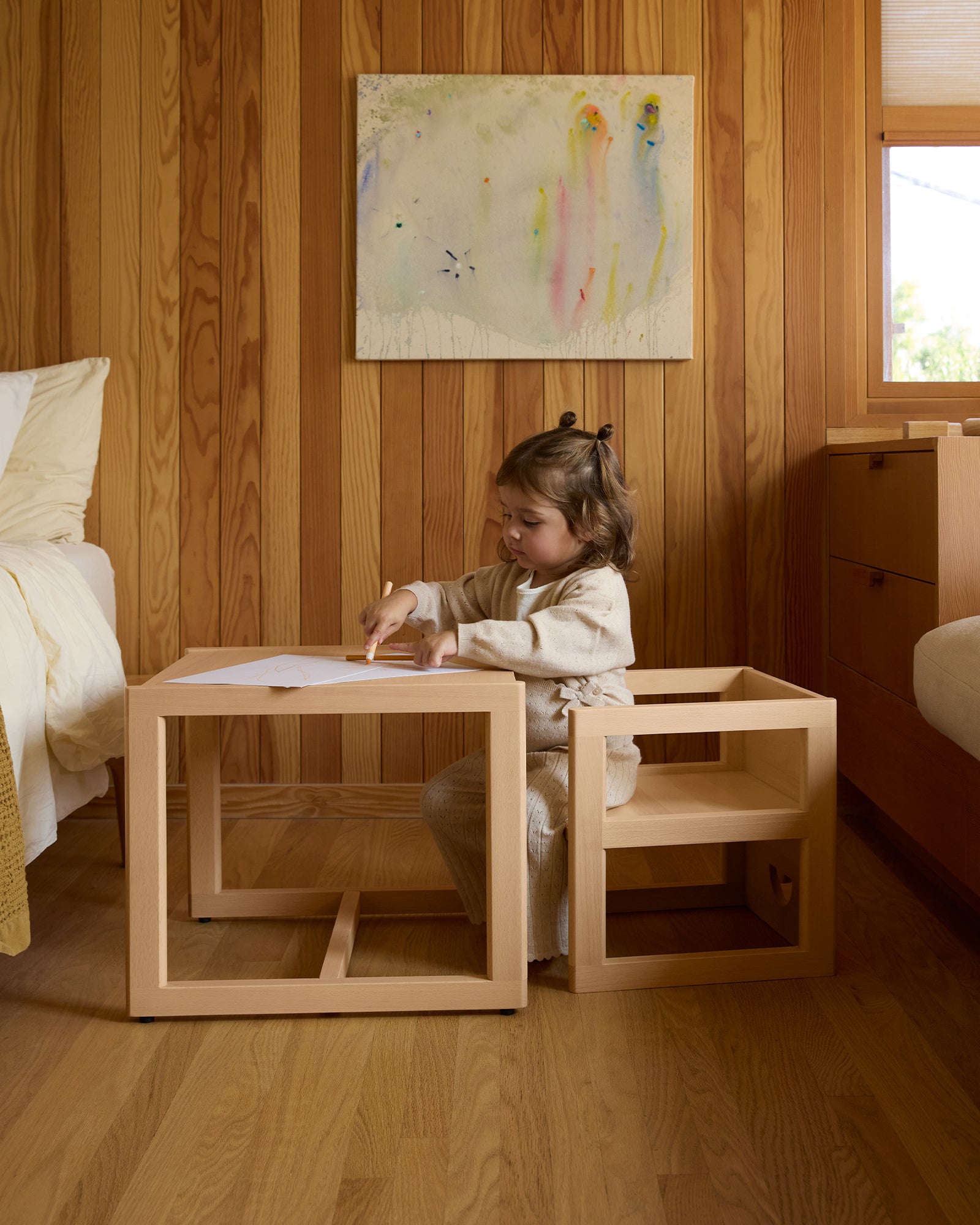 Toddler sitting on a Piccalio Montessori weaning table and reversible chair set in natural beech wood.