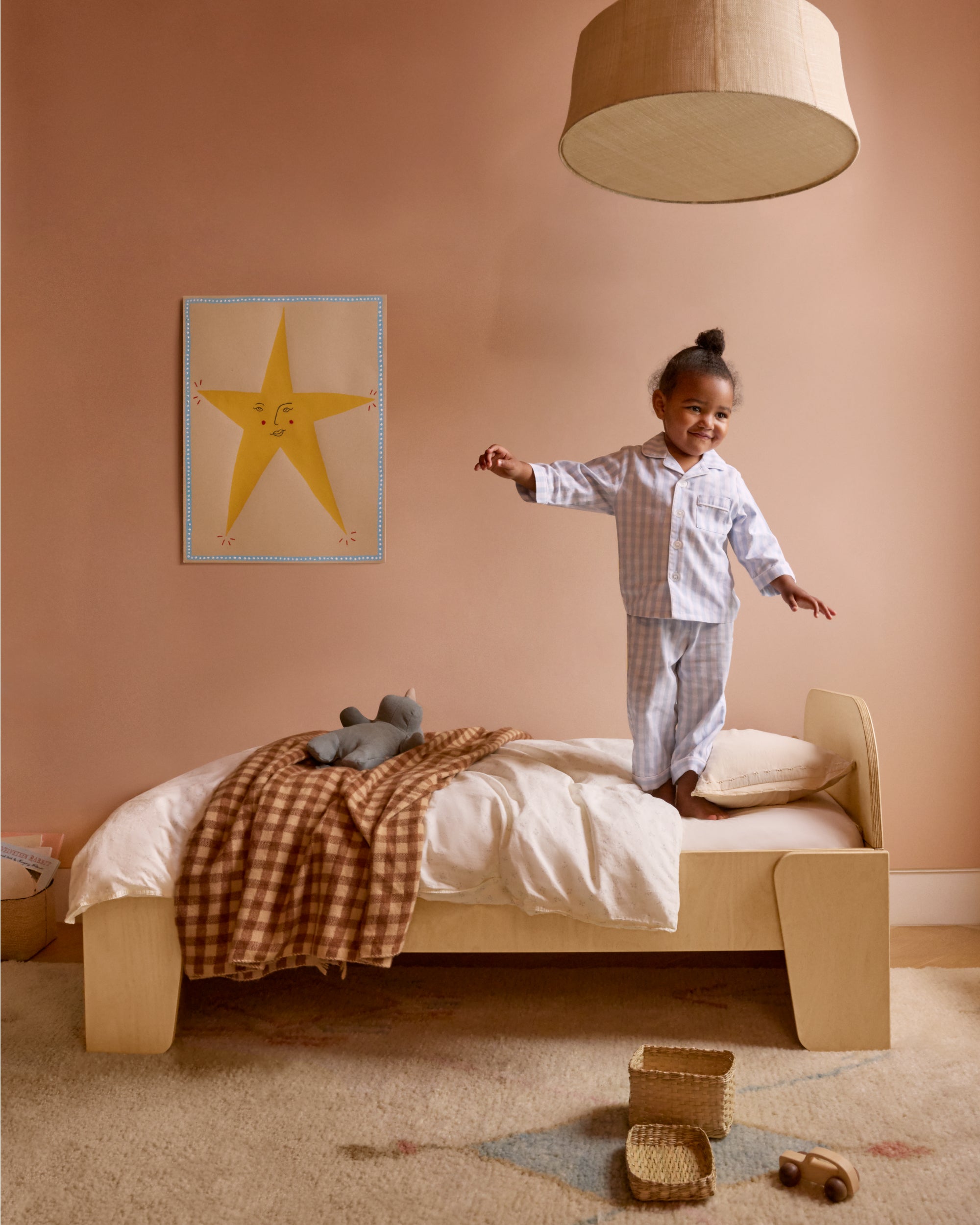 Piccalio Montessori bed in natural wood – Scandinavian-style with a toddler girl standing on the bed.