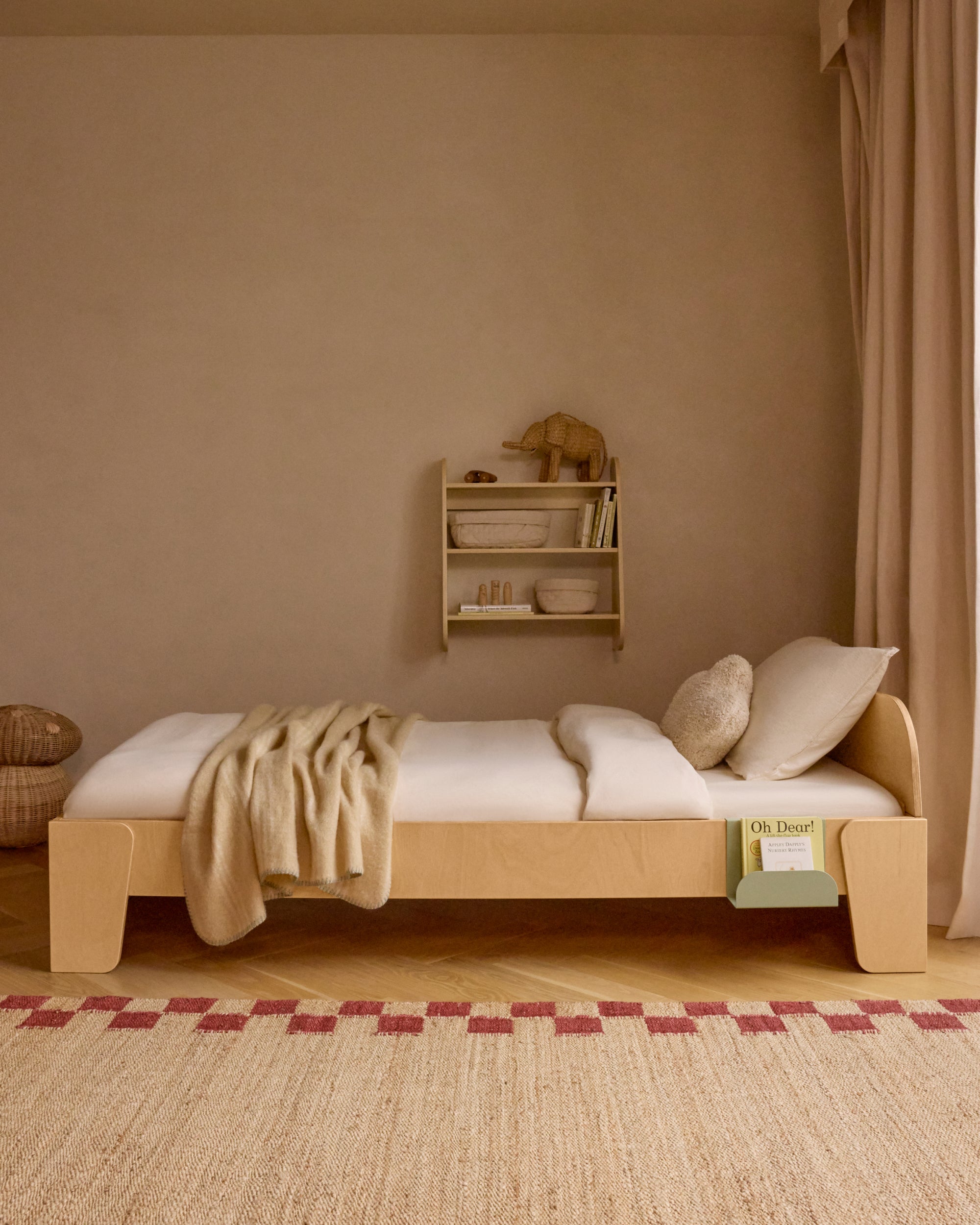 Piccalio Montessori floor bed in natural wood with a sage bed book hook to store books.