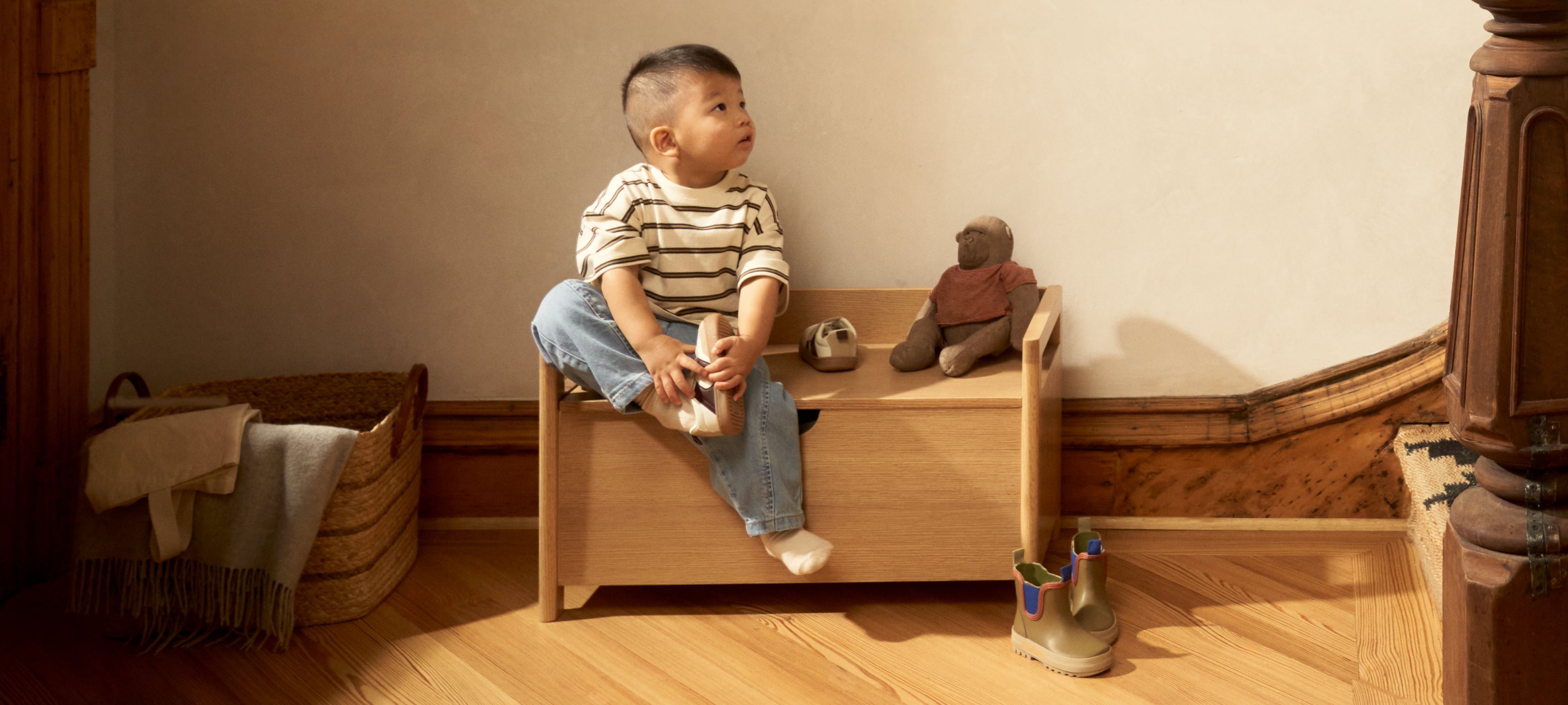 Piccalio Toy Box in natural wood with a toddler boy sitting on toy box.