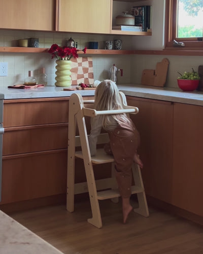 Kids foldable kitchen toddler tower in birch wood being used by two toddlers at the counter and sink