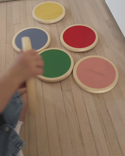 Toddler steps across a set of six colorful Piccalio wooden Stepping Stones laid out on the floor — a Montessori balance toy that supports gross motor skills and active indoor play.
