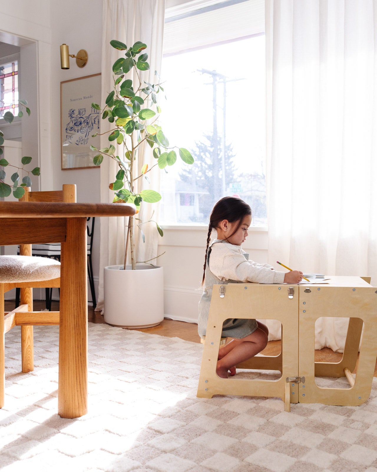 Piccalio convertible toddler tower in natural wood used by a toddler in its desk configuration for drawing.